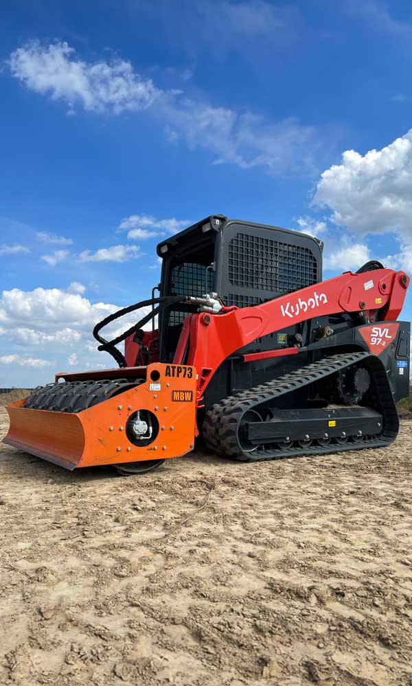 Kubota SVL97 compact track loader with roller attachment on a Charlotte job site