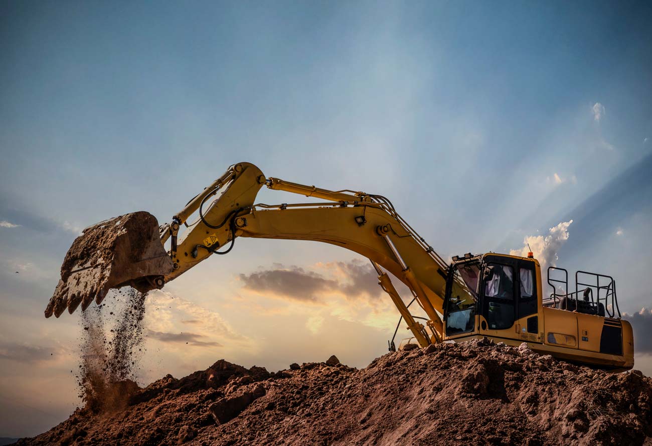 Excavator dumping soil at sunset on a Charlotte-area excavation job site