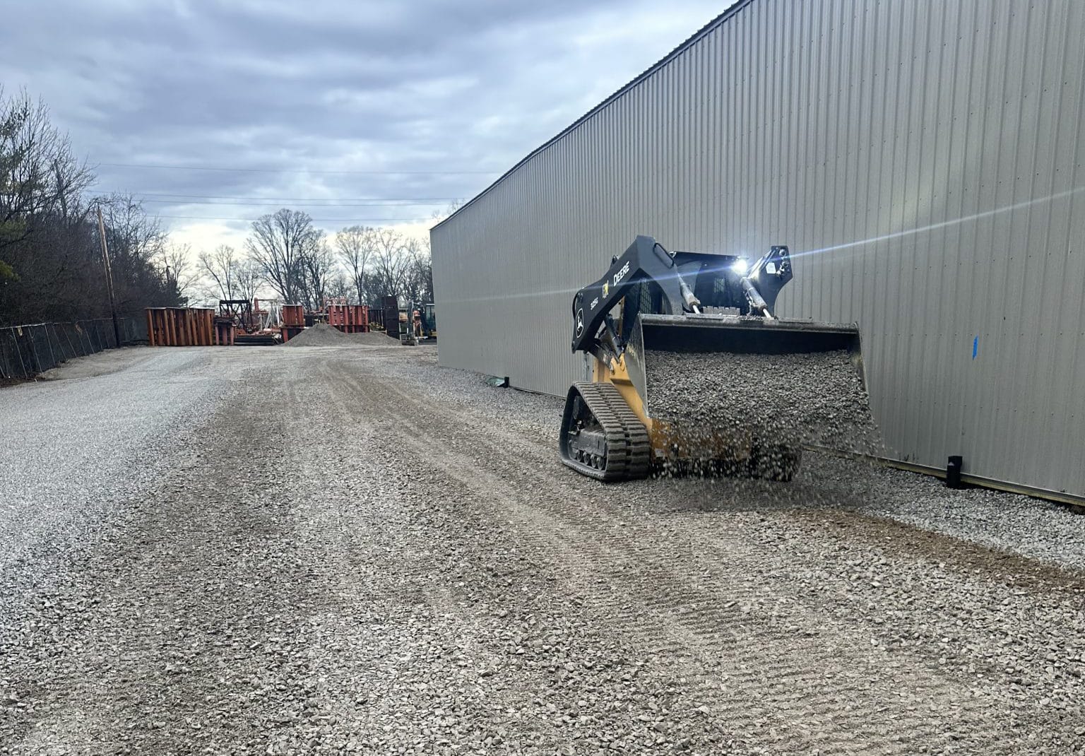 Skid steer spreading gravel for driveway and pad work in Charlotte